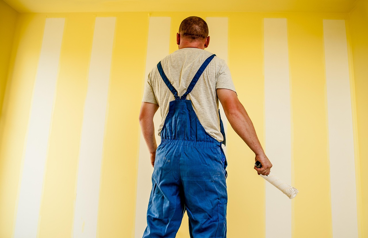 Saffraankleurige muur met moderne kunstwerken.